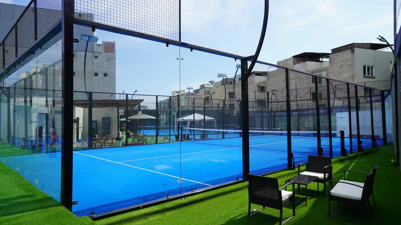 A padel court with chairs and tables set out on the grass beside it.