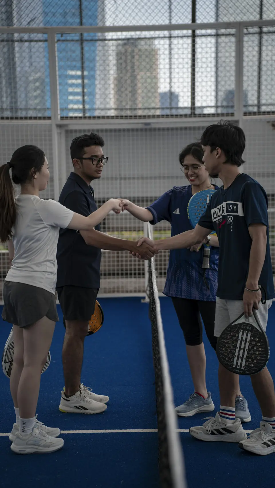 Four players shaking hands over the net at the end of a match.
